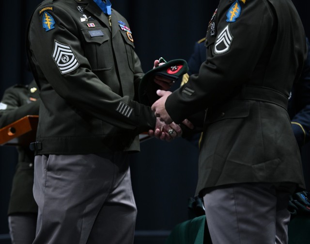 Command Sgt. Maj. Matthew O. Williams, Medal of Honor recipient, U.S. Army John F. Kennedy Special Warfare Center and School, presents a Green Beret to a student during a graduation ceremony and Regimental First Formation at the Crown Coliseum in...