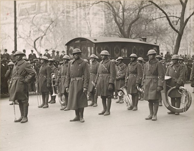 Soldiers assigned to the 369th Infantry Regiment band stand at rest as they wait to march up Fifth Avenue in New York City during a parade held to welcome the New York National Guard unit home, Feb. 17, 1919.