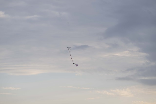 A small drone with a balloon attached flies across the sky at the Joint Counter-Small Unmanned Aircraft System University range at Fort Sill, Okla., Aug. 20, 2025. Students learn to shoot at balloons before they shoot the actual equipment.
