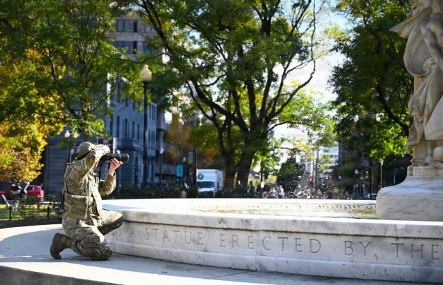 U.S. Air Force Tech. Sgt. Andrew Enriquez, a public affairs specialist with the 113th Wing, District of Columbia Air National Guard, gets into position to document a presence patrol in the Dupont Circle area, Washington, D.C., Nov. 3, 2025. About...