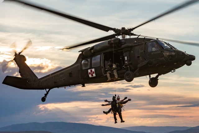 A U.S. Army HH-60 Black Hawk helicopter crew chief, assigned to U.S. Air Ambulance Detachment, 2nd Battalion, 158th Aviation Regiment, 16th Combat Aviation Brigade, raises volunteers from Central Washington Mountain Rescue via the hoist system...