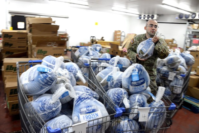 Sgt. Serun Tankisi, Army Corrections Brigade, grabs a turkey for a Thanksgiving meal basket as service members arrive to pick up the donated meals Nov. 18, 2025, at the Fort Leavenworth Commissary at Fort Leavenworth, Kansas. Photo by Prudence...