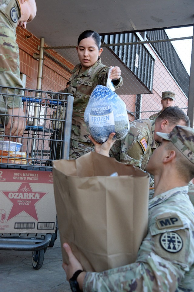 Sgt. Janelis Otero, Headquarters and Headquarters Company, U.S. Disciplinary Barracks Battalion (Corrections), hands a turkey to 2nd Lt. Kenneth Velez, A Company, USDB, while helping to distribute Thanksgiving meal baskets to fellow service...