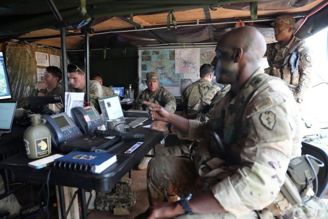 Col. Adisa King, forefront, 3rd Mobile Brigade Combat Team Commander, 25th Infantry Division, prepares for Joint Pacific Multinational Readiness Center (JPMRC 26-01) command and control (C2) on-the-move missions inside a mobile command post, which features a common operating picture displaying the warfighting function data feeds, on November 6, 2025, at Schofield Barracks, Hawaii. The unit’s follow-on exercise will feature Next Generation Command and Control (NGC2) software, which will allow applications to ingest and share C2 data across all the warfighting functions for the commander’s decision overmatch.  