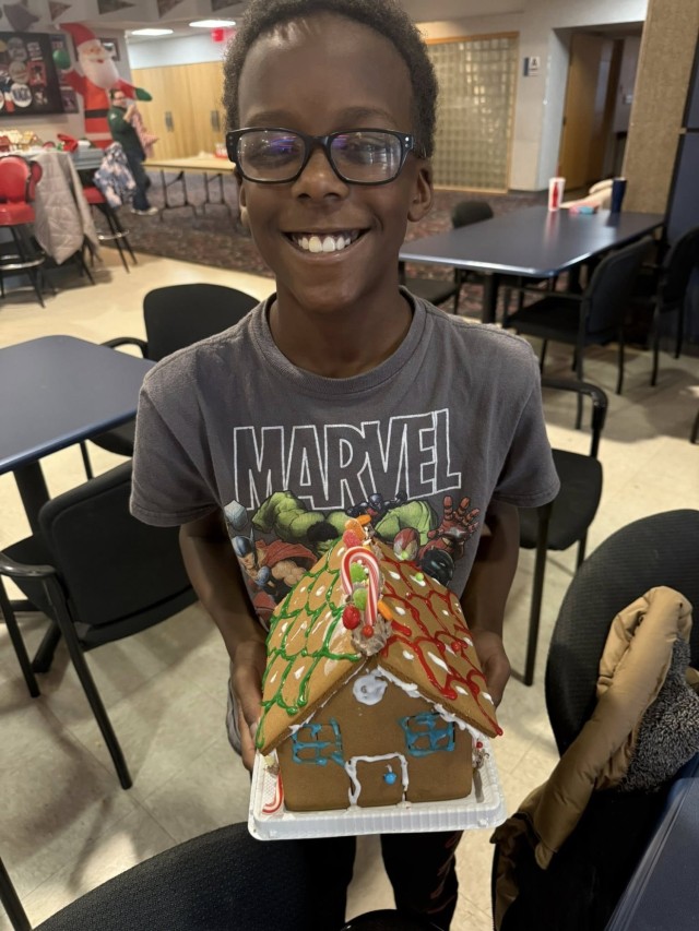 A gingerbread showdown contestant shows off their gingerbread house as Fort McCoy community members participate in the 2025 Breakfast with Santa, Gingerbread House Showdown event Dec. 5, 2025, at Fort McCoy, Wis. Dozens of Fort McCoy community...
