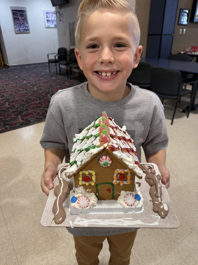 A gingerbread showdown contestant shows off their gingerbread house as Fort McCoy community members participate in the 2025 Breakfast with Santa, Gingerbread House Showdown event Dec. 5, 2025, at Fort McCoy, Wis. Dozens of Fort McCoy community...