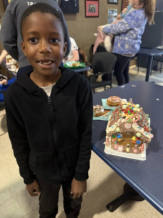 A gingerbread showdown contestant shows off their gingerbread house as Fort McCoy community members participate in the 2025 Breakfast with Santa, Gingerbread House Showdown event Dec. 5, 2025, at Fort McCoy, Wis. Dozens of Fort McCoy community...