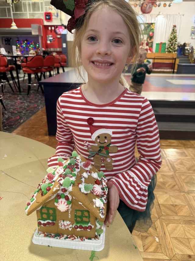 A gingerbread showdown contestant shows off their gingerbread house as Fort McCoy community members participate in the 2025 Breakfast with Santa, Gingerbread House Showdown event Dec. 5, 2025, at Fort McCoy, Wis. Dozens of Fort McCoy community...