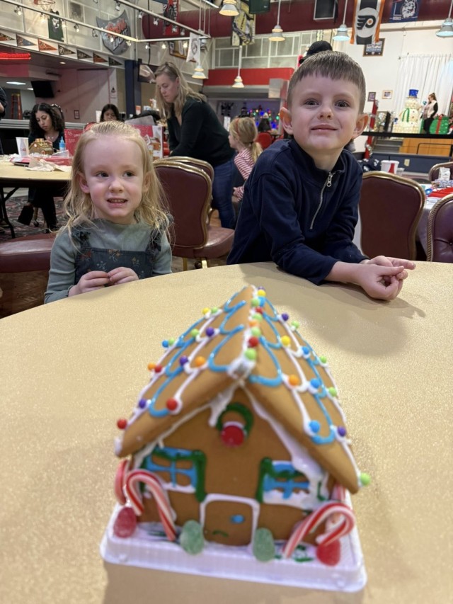 A gingerbread showdown contestant shows off their gingerbread house as Fort McCoy community members participate in the 2025 Breakfast with Santa, Gingerbread House Showdown event Dec. 5, 2025, at Fort McCoy, Wis. Dozens of Fort McCoy community...