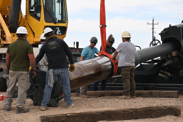Men moving gun barrell