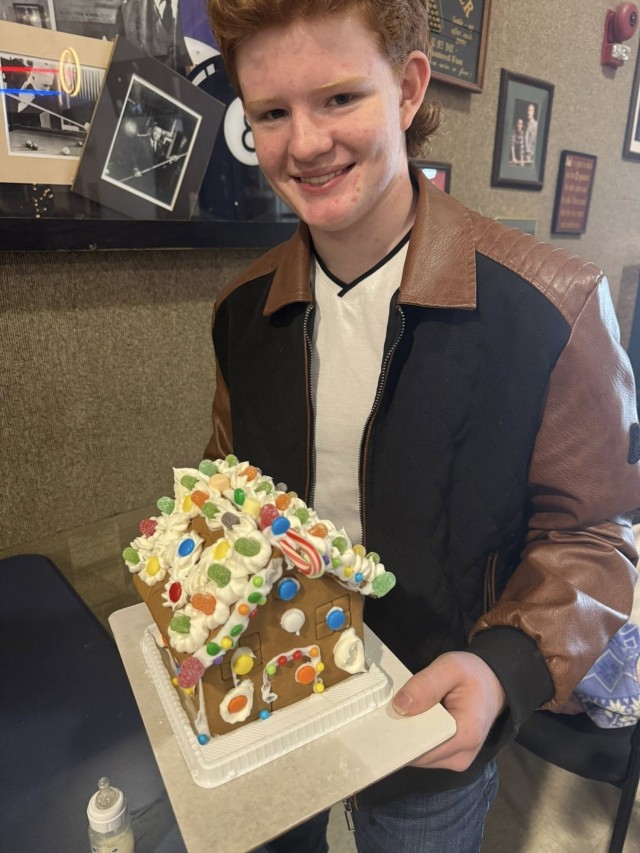 A gingerbread showdown contestant shows off their gingerbread house as Fort McCoy community members participate in the 2025 Breakfast with Santa, Gingerbread House Showdown event Dec. 5, 2025, at Fort McCoy, Wis. Dozens of Fort McCoy community...