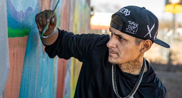 Artist Gabriel Armendariz paints a mural at an unhoused shelter in Espanola, NM, on December 6, 2026. This mural is titled "Turn the Corner" to represent the community's history and hope for the future.