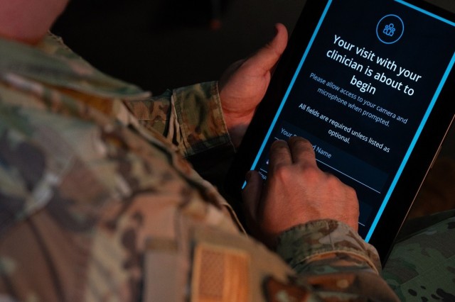 A member of the United States uniformed services uses an tablet to facilitate a doctors appointment.
