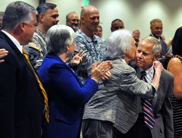 Jack Walker, deputy to the Garrison commander, hugs his wife Doris as their children Kevin Walker and Kathryn West smile and applaud after Walker's remarks upon being presented the Exceptional Civilian Service Award Aug. 8, 2013, at the Frontier...