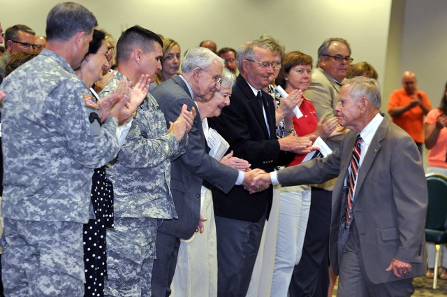 Lt. Gen. Michael Ferriter, commander of Installation Management Command, and others applaud as Civilian Aide to the Secretary of the Army for Kansas retired Lt. Gen. Robert Arter, with wife Lois, shakes hands with Jack Walker, deputy to the...