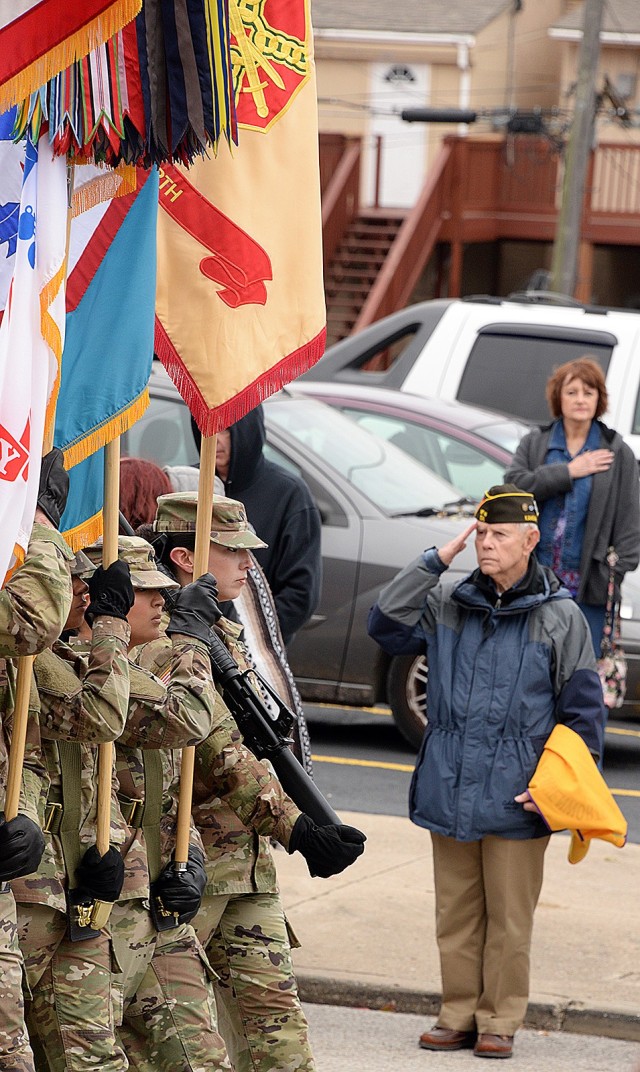 As the Fort Leavenworth contingent of troops enters the reviewing stand area, Deputy to the Garrison Commander Jack Walker salutes the flag held aloft by the Medical Department Activity Color Guard during the Veterans Day parade Nov. 11, 2017, in...