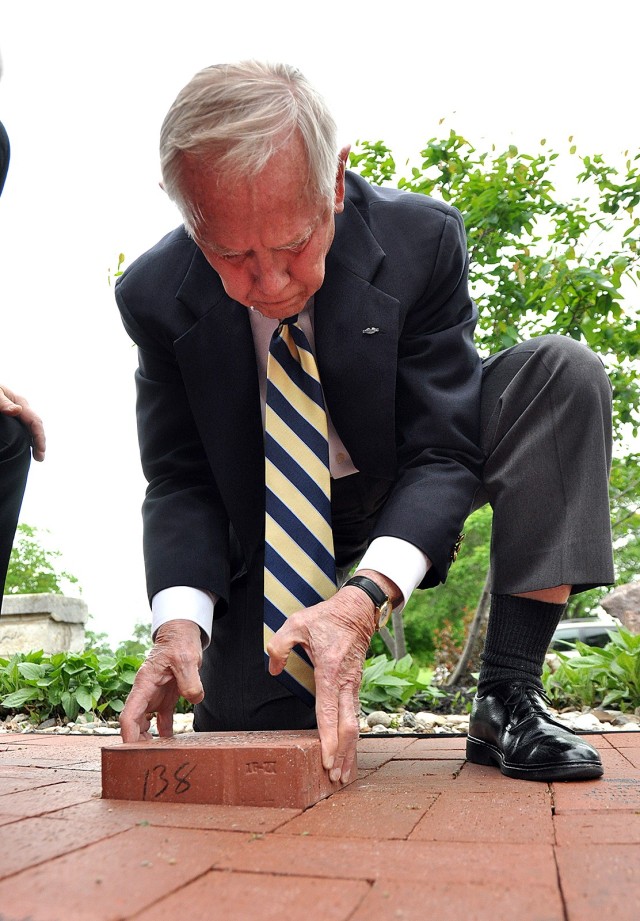 Deputy to the Garrison Commander Jack Walker places a brick, given in his honor by the Garrison team, during a brick installation ceremony for the Friends of the Frontier Army Museum Frontier Tribute Trail May 2, 2017, in front of the Frontier...