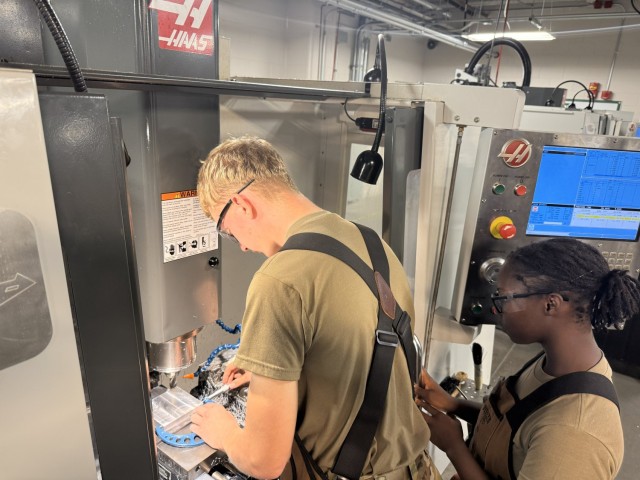 SSG Shane Grimes instructs PVT Charity Dragg and PV2 Evan Sharpe how to
validate cutting length and width to blueprint on the CNC mill at Fort Lee, Virginia, Oct. 8, 2025.