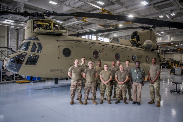The team responsible for the complete overhaul of a CH-47 Chinook helicopter that was battle damaged from a hard landing while serving in Iraq pose for a group photo in front of the helicopter at the Connecticut National Guard's 1109th Theater...