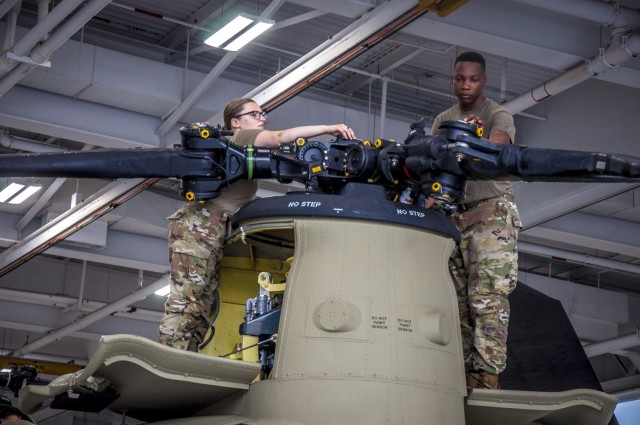 U.S. Army Spc. Kaitlin Cavanaugh and Sgt. Omar Sewell conduct maintenance on the forward rotor of a CH-47 Chinook helicopter that was battle damaged from a hard landing while serving in Iraq in the maintenance bay of the Connecticut National...