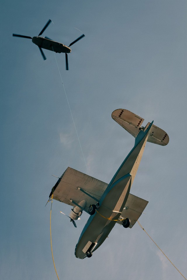 A U.S. Army CH-47 Chinook helicopter assigned to Bravo Company, 1st Battalion, 168th Aviation Regiment, 96th Aviation Troop Command, Washington National Guard, sling loads a PBY-5A Catalina amphibious aircraft from downtown Oak Harbor, Wash.,...
