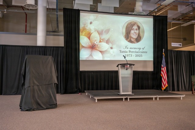 A memorialization ceremony is set up - an easel covered in drapes, a projector with memorial photo and text, a podium, and an American flag are pictured.