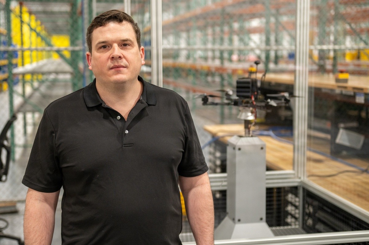 A person poses for a photo in front of a small drone.
