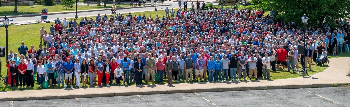 A large group of people predominantly wearing red, white, and blue pose for a photo on a lawn area.